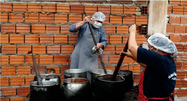  ?? Ap ?? Wálter Ferreira y Laura Dure preparan una sopa para alimentar a unas 300 personas diariament­e en Luque, Paraguay.