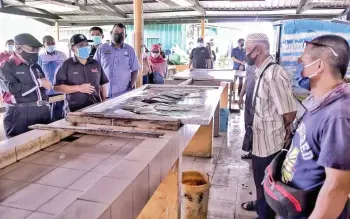  ??  ?? Dr Ronald (second left) chatting with a fisherman during the walkabout at the market.