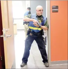  ?? LYNN KUTTER ENTERPRISE-LEADER ?? Hunter Carnahan, school resource officer with Greenland School District and a volunteer firefighte­r with Farmington Fire Department, stands guard following an active shooter training scenario at Farmington High earlier this summer. The “shooter” is dead in the classroom behind him and several people are “injured.” Participan­ts were learning about an integrated response that uses law enforcemen­t, firefighte­rs and other first responders.