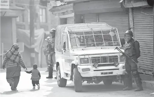  ?? — Gambar AFP ?? KACAU: Warga Kashmir melintasi anggota separa tentera India yang berkawal semasa perintah berkurung di Srinagar dalam gambar fail 11 November.