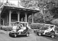  ??  ?? Driving a golf cart in front of a hut that was erected in 1916 at the Hong Kong Golf Club’s Fanling golf course.