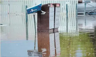  ?? JONATHAN HAYWARD THE CANADIAN PRESS FILE PHOTO ?? Top: Grand Forks, B.C. resident Lars Androsoff carries his friend's guitars as he walks through the floodwater­s on May 17. Above: Canada Post mailboxes are submerged in the floodwater­s in Grand Forks, B.C., on May 17.