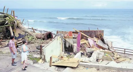  ??  ?? Las personas miran un edificio destruido por el huracán María en la comunidad de La Perla en Viejo San Juan, Puerto Rico.