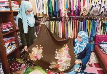  ?? PIC BY ABNOR HAMIZAM ?? Businesswo­man Noor Azizah Mamat (left) with a customer at her shop in Negri Sembilan.