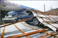  ?? ELIZABETH CONLEY — HOUSTON CHRONICLE VIA AP ?? Parts of a roof sit on top of a car parked at Blessings Tire and Auto Care following Hurricane Nicholas Sept. 14 in Bay City, Texas. According to the owner of the business, he wasn’t sure where the roof came from.