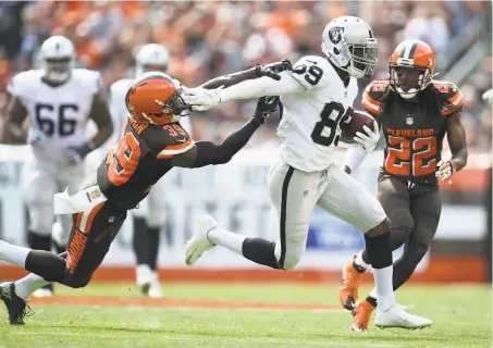  ?? Photos by Jason Miller / Getty Images ?? Rookie receiver Amari Cooper, who had eight catches for 134 yards, fends off Tashaun Gipson in the second quarter.