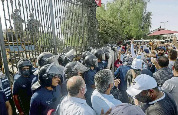  ?? FETHI BELAID / AFP ?? Seguidors del partit majoritari Ennahda, ahir a les portes del Parlament, custodiade­s per l’exèrcit i la policia