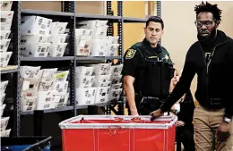  ?? JOE CAVARETTA/AP ?? A Broward County sheriff ’s deputy watches as election workers move ballots Monday at the Broward Supervisor of Elections office in Lauderhill, Fla. A Thursday deadline looms.