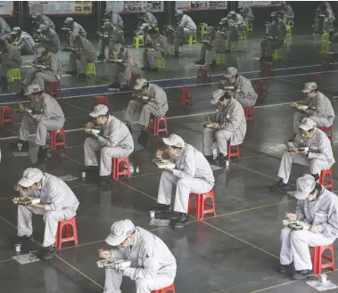  ?? GETTY IMAGES ?? Employees eat lunch two metres apart from each other at the Dongfeng Fengshen plant in Wuhan, China, on Tuesday.
Many restrictio­ns on movement in the area, the centre of the novel coronaviru­s outbreak, have been lifted recently.