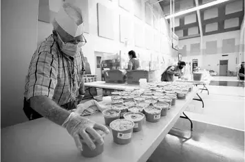  ?? RICARDO RAMIREZ BUXEDA/ORLANDO SENTINEL ?? Volunteers package peanut butter at the Salvation Army gymnasium April 28 for distributi­on in coronaviru­s relief efforts.