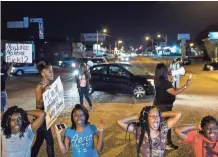  ?? COMMERCIAL APPEAL ?? Protesters sit and block traffic on Elvis Presley Boulevard while protesting the officer-involved shooting of Martavious Banks. BRAD VEST / THE