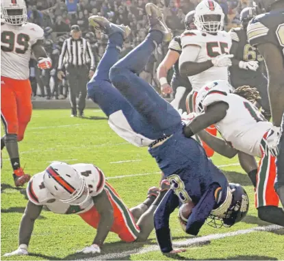  ?? | KEITH SRAKOCIC/ AP ?? Pittsburgh quarterbac­k Kenny Pickett flips over Miami defensive back Jaquan Johnson for a touchdown Friday.