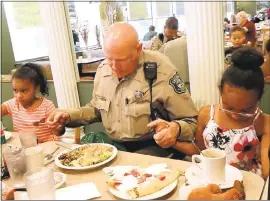  ??  ?? Rick Chaeff says grace with the Robinson family before lunch at Goodies Good Eats in Campbell. At left is Ziggy Robinson, 5, and her sister Isys Robinson, 7, at right.