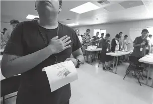  ?? ERIC GAY/ASSOCIATED PRESS ?? Immigrants say the Pledge of Allegiance in a writing class Tuesday at the U.S. government’s newest holding center for migrant children in Carrizo Springs, Texas. Following breakfast, children play soccer and then have classes held in trailers.