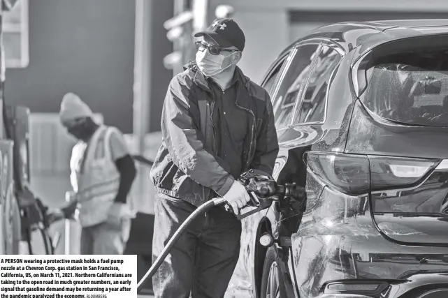  ?? BLOOMBERG ?? A PERSON wearing a protective mask holds a fuel pump nozzle at a Chevron Corp. gas station in San Francisco, California, US, on March 11, 2021. Northern California­ns are taking to the open road in much greater numbers, an early signal that gasoline demand may be returning a year after the pande mic paralyzed the economy.