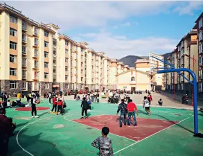  ??  ?? Des enfants jouent sur le terrain de sport dans un site de réinstalla­tion.