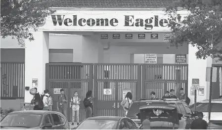  ?? PHOTOS BY JOE RAEDLE/GETTY IMAGES ?? Students arrive at Marjory Stoneman Douglas High School on Wednesday, the first day of school. Students will find new cameras, locks and eventually more fencing on the grounds.