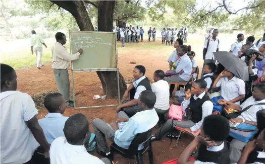  ?? ?? Learners at Makuya Secondary School sit under a tree, their classroom, listening to their teacher, on 14 January 2015. Students from Makuya village, in the Vhembe district in Limpopo, arrived at a school with no classrooms, no chairs and no desks. The school only has 10 classrooms and cannot cope with the annual increase in student enrolment. Photo: Suprise Mazibila/sowetan/gallo Images