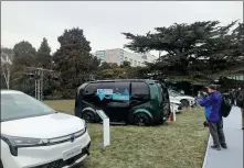  ?? LI FUSHENG / CHINA DAILY ?? Visitors look upon electric vehicles displayed outside an industry forum in Beijing in January.