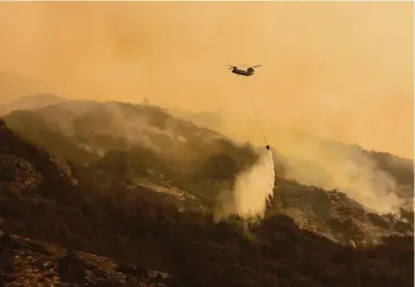  ?? Patrick T. Fallon / AFP via Getty Images ?? A Boeing CH-47 helicopter carries water Saturday to drop on the KNP Complex in Sequoia National Park.