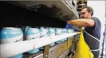  ?? TY GREENLEES / STAFF ?? Gregory Craig lines up Trotwood Lager cans after they went through a can-washing machine at Warped Wing Brewing Company in Dayton.