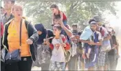  ?? AP ?? A group of migrants walk along a dusty road towards a transit centre after crossing the border from Greece to Macedonia on Monday.