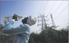  ?? MANISH SWARUP/AP ?? A WORKERS QUENCHES HIS THIRST next to power lines as a heatwave continues to lashes the capital, in New Delhi, India on Monday.