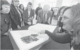  ?? Christian Gooden / St. Louis Post-Dispatch ?? Kitty Mandis, right, presents pages of a bound heritage copy of a section of the St. John’s Bible at the Arch Diocese Headquarte­rs in Shrewsbury, Mo.