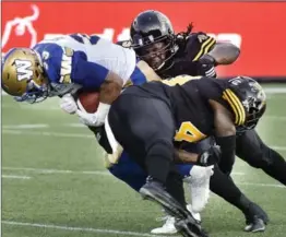  ?? JOHN RENNISON, THE HAMILTON SPECTATOR ?? Drake Nevis, background, and Larry Dean bring down Blue Bomber Andrew Harris in the second quarter of a game in July.