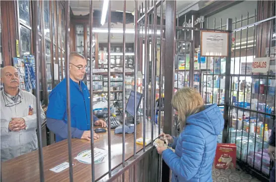  ?? Emiliano lasalvia ?? En la histórica farmacia de Horacio Torina (izquierda), las rejas separan el mostrador del público