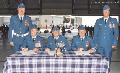  ?? PHOTO : IMAGERIE CPL CALVÉ ?? Les colonels Guillette ( assis à gauche) et Boucher ( assis à droite) signent les documents officialis­ant le changement de commandeme­nt en compagnie du commandant de la 1re Division aérienne du Canada, le major- général Drouin ( au centre). Ils sont...