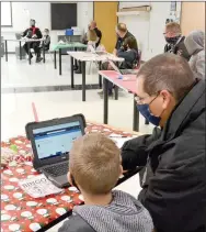  ??  ?? Sgt. John Langham, school resource officer, assists a student shopping online for the annual Shop with a Cop event held differentl­y this year because of covid-19 restrictio­ns.