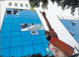  ?? Mohamed Ben Khalifa ?? The Associated Press A man stands outside the damaged headquarte­rs of the national oil company after an attack by gunmen in Tripoli, Libya, on Monday.