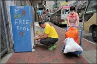  ?? The Associated Press ?? FOOD SOURCE: Ahmed Khan puts foods inside a refrigerat­or Nov. 18 at Woosung Street in Hong Kong's old-school neighborho­od of Jordan. Khan, founder of a sports foundation on the same street, said he was inspired to create a community refrigerat­or after seeing a film about others doing the same thing. He found the refrigerat­or at a nearby refuse collection point and painted it blue.