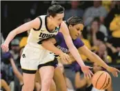  ?? MATTHEW PUTNEY/AP ?? Iowa guard Caitlin Clark, left, steals the ball from Holy Cross guard Simone Foreman in Saturday’s matchup in Iowa City, Iowa.