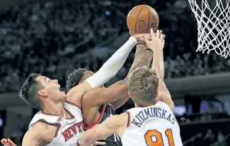  ?? KATHY WILLENS/THE ?? New York Knicks centre Willy Hernangome­z (14) and Knicks forward Mindaugas Kuzminskas (91) block a shot by Toronto Raptors guard DeMar DeRozan in the first half of an NBA basketball game at Madison Square Garden in New York.