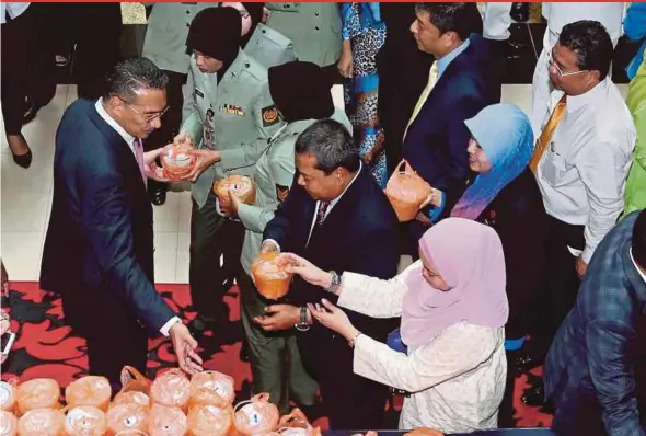  ?? PIC BY ZULFADHLI ZULKIFLI ?? Defence Minister Datuk Seri Hishammudd­in Hussein (left) distributi­ng ‘bubur lambuk’ to his ministry’s staff in Kuala Lumpur yesterday.