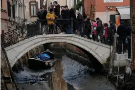  ?? ?? Tourists cross a bridge over a noticeably empty canal during a severe low tide in Venice, Italy. Photograph: Manuel Silvestri/Reuters