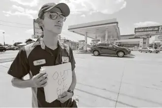  ?? Tony Gutierrez / Associated Press ?? Bryan Herrera holds a makeshift sign Thursday at a Shell station in north Dallas to wave away motorists seeking gasoline after the station ran out.