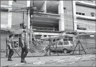  ?? AP/REY BANIQUET ?? In this photo provided by the Presidenti­al Photograph­ers Division, Malacanang Palace, police officers walk past a damaged building Sunday, two days after it was rocked by a powerful earthquake late Friday in Surigao del Norte province in southern...