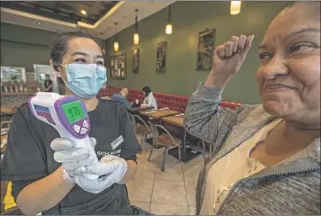  ?? Mel Melcon Los Angeles Times ?? CUSTOMER Grace Magallon, 63, right, of East Los Angeles reacts after having her temperatur­e taken with an infrared thermomete­r by Sophia Huang, a supervisor at Sichuan Impression restaurant in Alhambra.