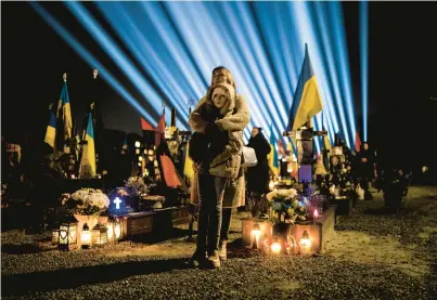  ?? PETROS GIANNAKOUR­IS/AP ?? A woman and her daughter listen to prayers for fallen soldiers at a service Thursday in Lviv, Ukraine.