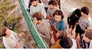  ?? AP file ?? Refugees, right, gather on one side of a fence to talk with internatio­nal journalist­s about their journey that brought them to the Island of Nauru. —