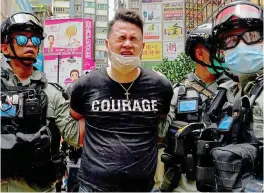 ??  ?? A Hong Kong protester winces from pepper spray as he is arrested