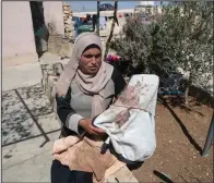  ?? ?? Palestinia­n mother Baraa Hamamdi holds her injured son’s bloodstain­ed clothes that were left behind after Mohammed was evacuated to an Israeli hospital following the attack.