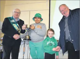  ?? (Photo: Katie Glavin) ?? John Murphy and Brendan Buckley of Fermoy St Patrick’s Day parade, presenting Clondulane NS students Liam and Mia with the trophy for ‘Best Overall’ prize from the 2023 parade.