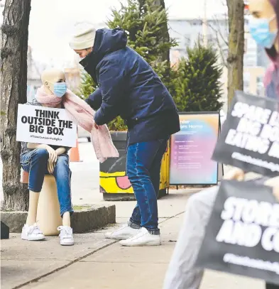  ?? NATHAN DENETTE / THE CANADIAN PRESS ?? Jacob Gawrysiak adjusts a sign in Toronto pleading for action to support local businesses during the pandemic.