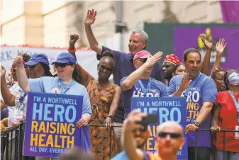  ?? Dia Dipasupil / Getty Images ?? NYC Mayor Bill de Blasio (center) and his wife Chirlane McCray join police, fire and hospital workers in a tickertape parade to honor those who played a crucial role during the pandemic.