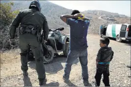  ?? Jae C. Hong ?? The Associated Press A Guatemalan father and son who crossed the U.s.-mexico border illegally are apprehende­d June 28 by U.S. Border Patrol in San Diego. California will introduce group trials on Monday for people charged with entering the country...