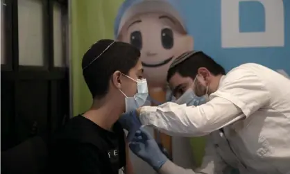  ?? Photograph: Maya Alleruzzo/AP ?? A 14-year-old Israeli receives a third booster shot of the coronaviru­s vaccine in Jerusalem. Israel was first to press ahead with a third booster dose.